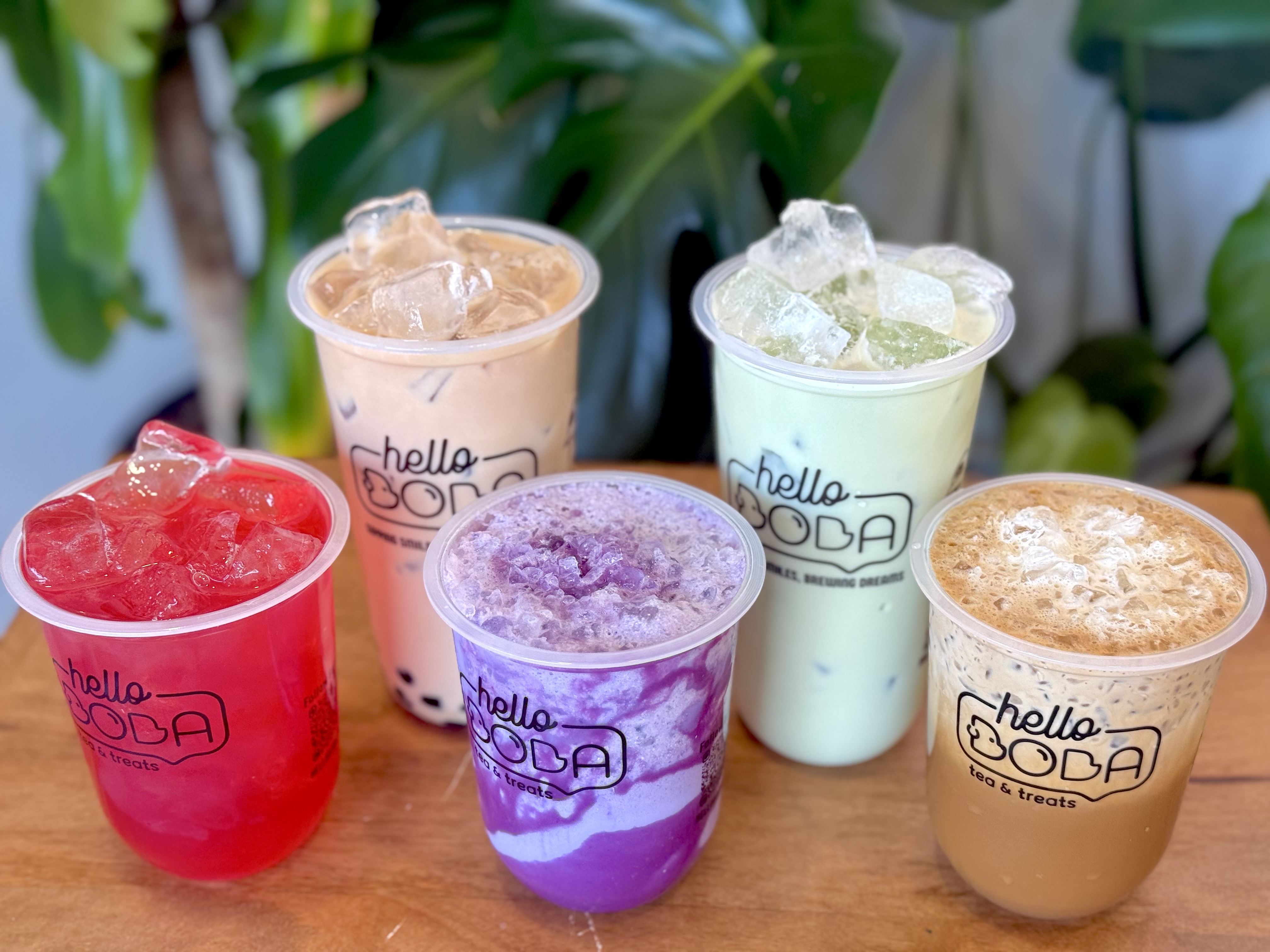 Colorful Hello Boba drinks lined up on a wooden table